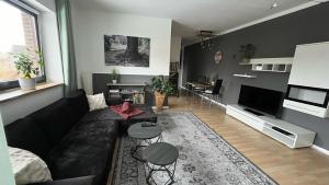 sala de estar con sofá negro y mesa en Ferienwohnung Talblick, en Bad Lauterberg