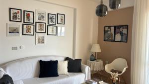 sala de estar con sofá blanco y cuadros en la pared en Casa con vista mare en Vlorë