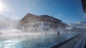 two people in a swimming pool in front of a building at Feriengut Unterhochstätt in Schwendt