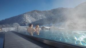 Dos personas están sentadas en un jacuzzi en una fuente termal en Feriengut Unterhochstätt, en Schwendt