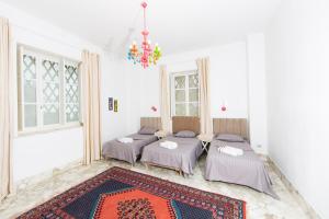 a group of four beds in a room with a rug at Appartement privé dans une grande maison d'hote in La Marsa