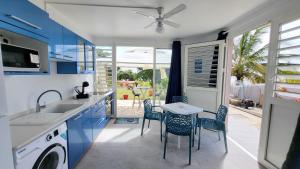 una cucina con armadi blu, tavolo e sedie di Votre Cocon Océan : Studio bien aménagé à louer a Sainte-Luce