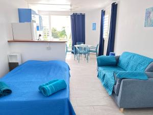 un soggiorno con letto blu e divano di Votre Cocon Océan : Studio bien aménagé à louer a Sainte-Luce