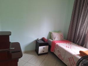 a small bedroom with a bed and a night stand at Hostel Santa Luzia in Viçosa