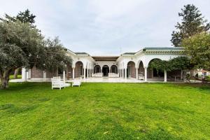 a house with a green yard with two white chairs at Appartement privé dans une grande maison d'hote in La Marsa