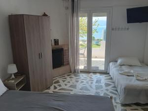 sypialnia z 2 łóżkami i przesuwnymi szklanymi drzwiami w obiekcie Flora's Beach House Your House On The Beach w mieście Amarynthos