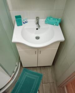 a white sink in a bathroom with a green rug at Apartments Vladika - Oldtown in Novi Sad