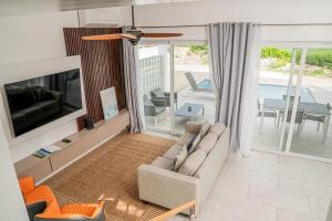 Villas with Private Pool 5 min to Grace Bay beach في Long Bay Hills: غرفة معيشة مع أريكة وتلفزيون
