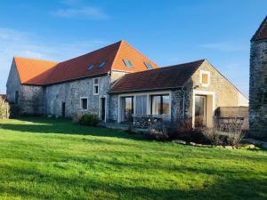 een stenen huis met een oranje dak op een groen veld bij La Grange du Flot in Tardinghen