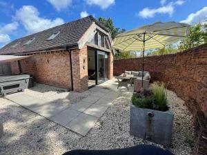 a patio with an umbrella next to a brick wall at Luxury private FARM BARN, Airport, NEC 