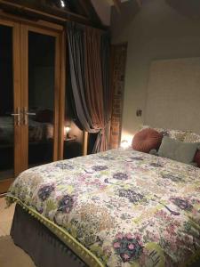 a bedroom with a bed with a floral bedspread at Luxury private FARM BARN, Airport, NEC 