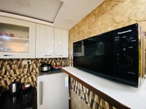 a kitchen with a microwave and a refrigerator at Rudhraksh Villa 4BR- Perfect Vacay Villa in Mussoorie