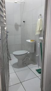 a white bathroom with a toilet and a sink at Kitinete Aconchegante in Porto De Galinhas