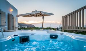 a hot tub with an umbrella on a patio at Milia Gi Suites in Pollonia