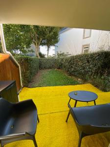 un patio con 2 sillas y una mesa en una planta amarilla en Appartement cosy rénové 4 personnes en centre ville Wifi inclus, en Quiberon