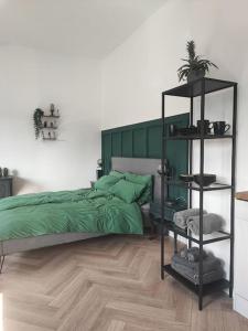 - une chambre avec un lit vert et une étagère noire dans l'établissement Stilvolles Appartment in Hagen, à Hagen