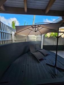 a patio with an umbrella and chairs on a deck at Lamary au François avec SPA in Le François