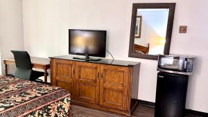 a room with a television on a dresser with a bed and a mirror at Executive Inn in Dallas