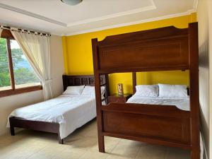 um quarto com 2 beliches e uma parede amarela em Casa vacacional em Loja