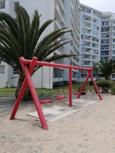 a swing set on the beach with a palm tree at Apartamento en Laguna del Mar in La Serena