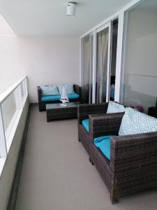 a living room with two wicker couches and a balcony at Apartamento en Laguna del Mar in La Serena