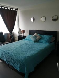 a bedroom with a bed with a blue comforter at Apartamento en Laguna del Mar in La Serena