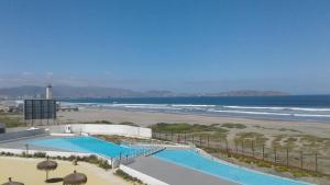 vistas a una playa con piscina y un faro en Apartamento en Laguna del Mar, en La Serena