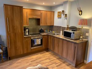 a kitchen with wooden cabinets and a microwave at Beautifully unique town centre apartment in Macclesfield