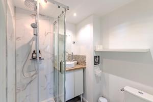 ein weißes Bad mit einer Dusche und einem Waschbecken in der Unterkunft Charmant studio à deux pas de la gare - Le Nichoir in Rennes
