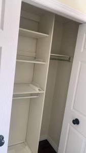 a white closet with empty shelves and a door at Cozy Homestay Waterloo Airport II in Kitchener