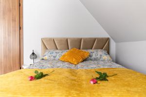 a bed with a yellow blanket and two flowers on it at Jaki Widok! in Maniowy