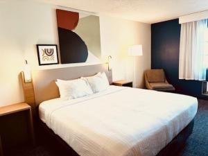 a hotel room with a large bed and a chair at Spark by Hilton Modesto in Modesto