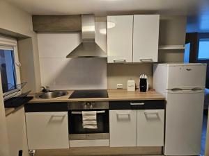 a kitchen with white cabinets and a sink and a refrigerator at Leilighet nær flyplass og Ålesund sentrum in Ytterland