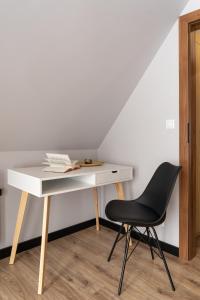 un escritorio blanco y una silla negra en una habitación en Jaki Widok! en Maniowy