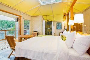 ein Schlafzimmer mit einem großen weißen Bett und einem Balkon in der Unterkunft Rockwater Secret Cove Resort in Halfmoon Bay