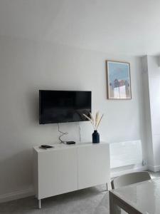 ein weißes Wohnzimmer mit einem TV an der Wand in der Unterkunft Gîte de La baleine in Luc-sur-Mer