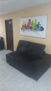 un sofá negro en una habitación con una pintura en la pared en hotel casa del conductor doña silvia, en Cartagena de Indias