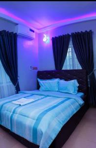D'EXQUISITE APARTMENTS في إيبادان: غرفة نوم مع سرير مع إضاءة أرجوانية