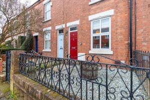 a red door on a brick house with a fence at 3BR Home with Free Parking in Spon End