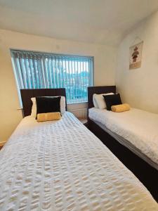 two twin beds in a room with a window at B43 Cosy Home - Contractor-Family Stays Near Bhm City-Off Road Parking Free Wi-fi in Holly Lane