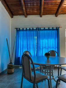 tavolo da pranzo con sedie e tenda blu di El Ocaso Villa Giardino a Villa Giardino