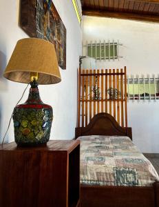 una lampada seduta su un tavolo accanto a un letto di El Ocaso Villa Giardino a Villa Giardino