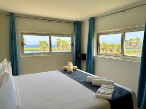 ein Schlafzimmer mit einem großen Bett mit zwei Fenstern in der Unterkunft MERAKII SEAVIEW ESCAPE CURACAO in Willemstad