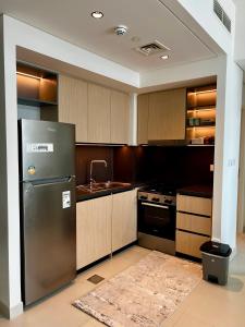 a kitchen with a stainless steel refrigerator and wooden cabinets at Brand New 1BHK Near Burj Khalifa-Burj Crown tower in Dubai