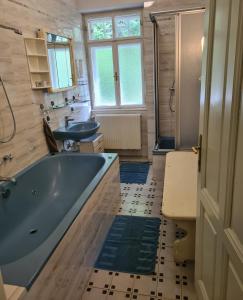 a bathroom with a blue tub and two sinks at Villa Waldheimat in Unter Adlitzgraben