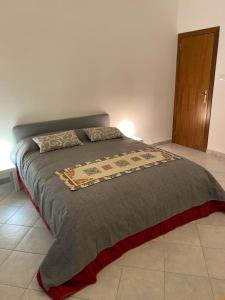 een slaapkamer met een bed met een grijze deken bij Casa Marconi 3, centrale, parking gratuit en rue. in Aragona