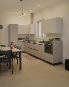 een keuken met witte kasten en een tafel en een eetkamer bij Casadoria34 - Appartamento da 70 mq in Mola di Bari