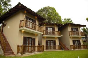 a house with wooden balconies and a yard at Vila dos Caetés - Suíte 03 - Barra do Sahy in Barra do Sahy