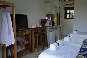 um quarto com duas camas e uma televisão e uma cozinha em Vila dos Caetés - Suíte 03 - Barra do Sahy em Barra do Sahy