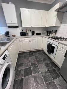 a kitchen with white cabinets and a washing machine at Stylish & Centrally Located in Chester-le-Street